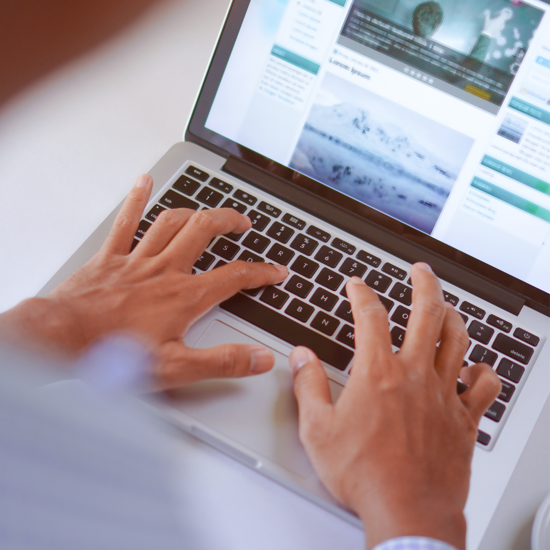 Person typing on laptop with website open.